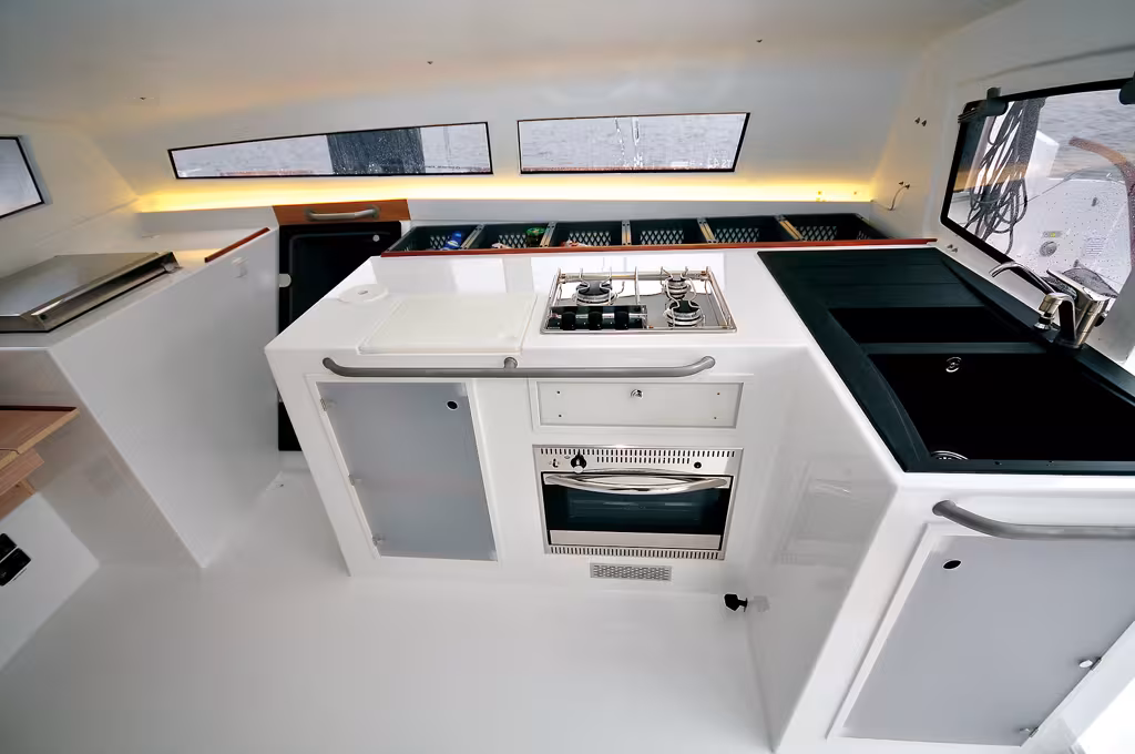Le mobilier est structurel ; les solutions simples ont été retenues (cf. le rack de paniers amovibles au fond), l'agrément de cette cuisine semi-outdoor est remarquable. On remarque la porte étanche d'entrée dans le flotteur.
