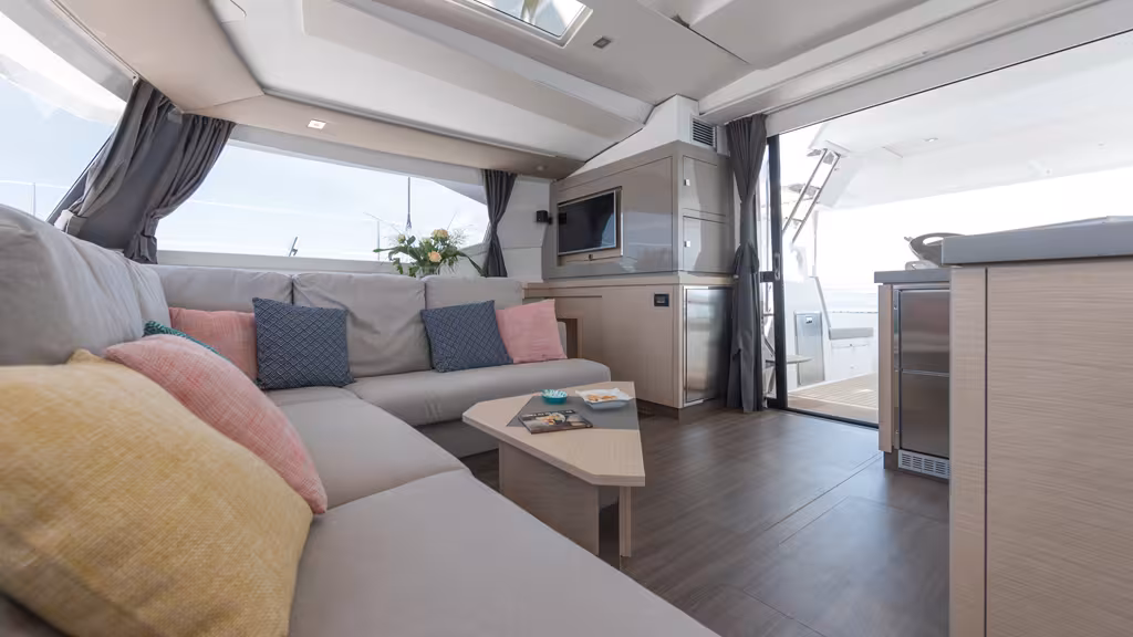 Le salon de pont ouvre largement sur le cockpit ; la sellerie a été revisitée. Notez les puits de lumière dans le plafond du roof, qui permettent une lecture directe du réglage des voiles depuis l'intérieur.